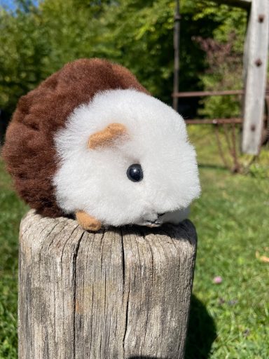 Stofftier in Form eines Igel mit braunem und weißem Fell auf einem Pfosten.